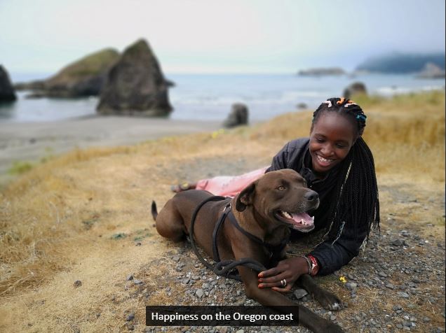 Rejoice, a black woman, with a dog on the Oregon coast
